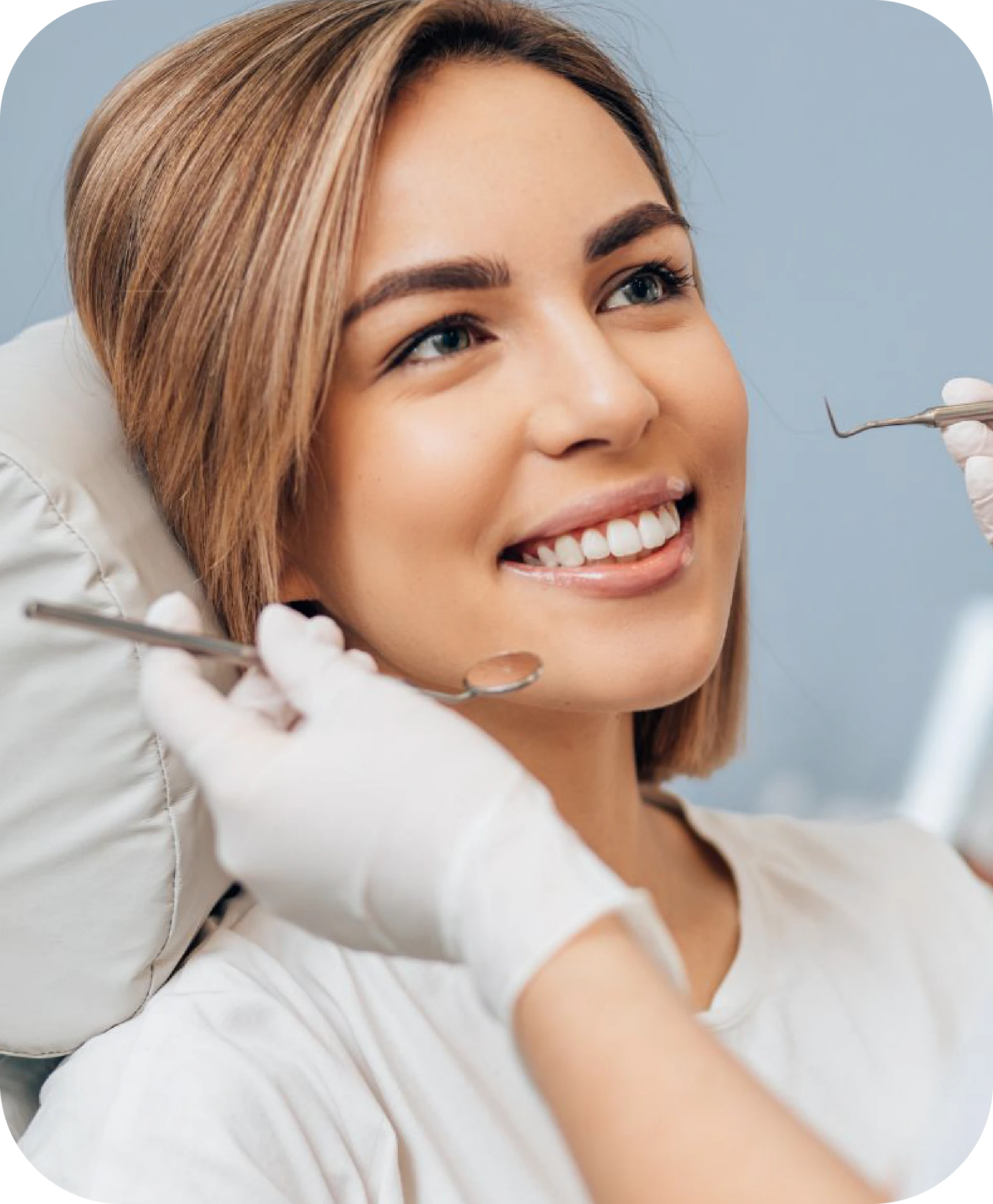 smiling woman sitting in dental chair being examined by dentist