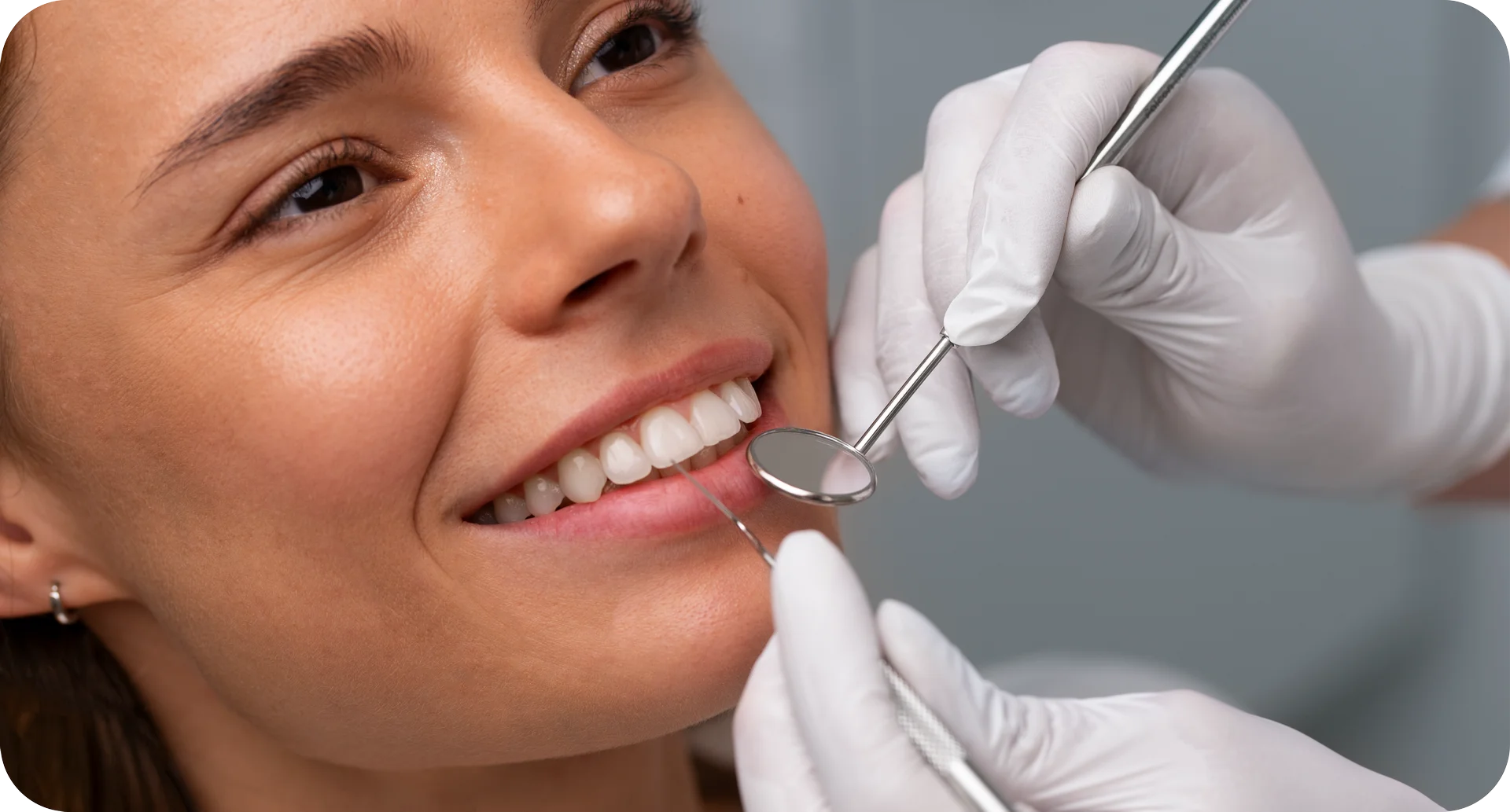 smiling woman having teeth checked with dental tools